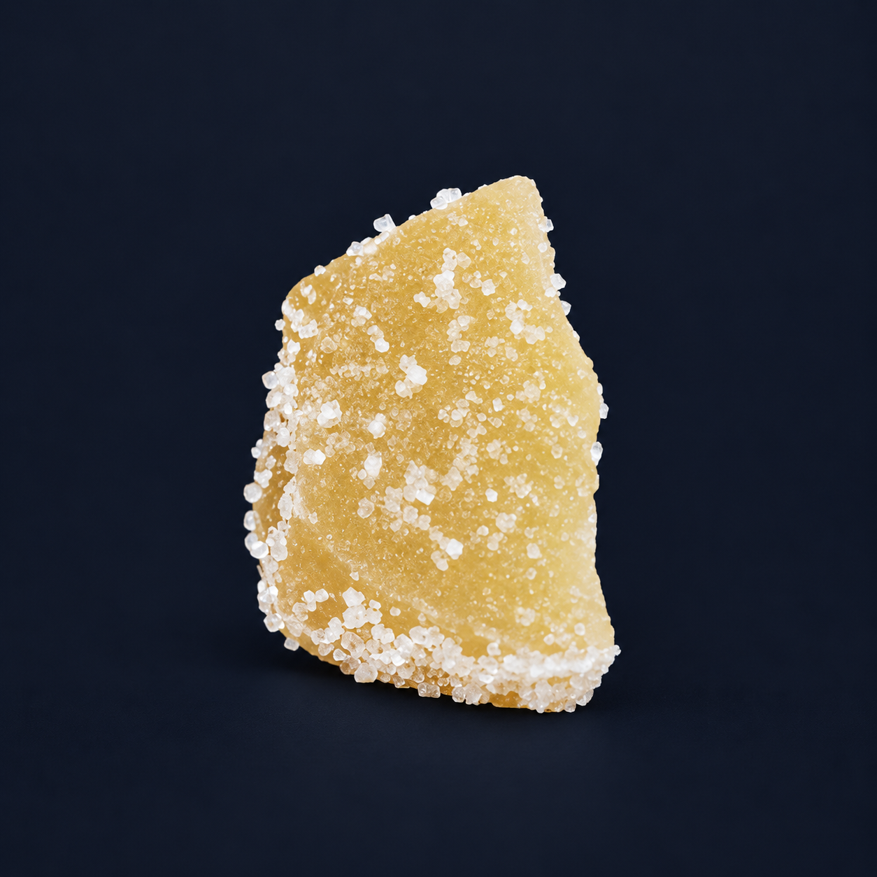 Single crystallised Thai ginger chunk on a dark navy background