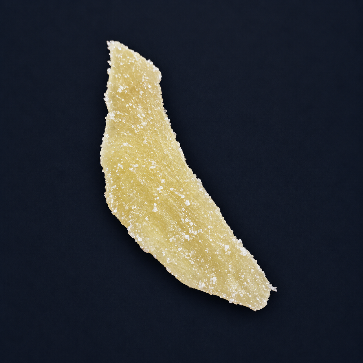 Single crystallised Thai ginger slice on a dark navy background