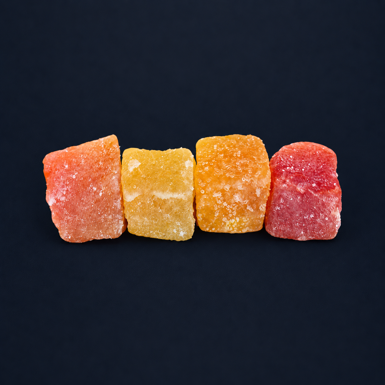 Four colourful diced papaya pieces on a dark navy background
